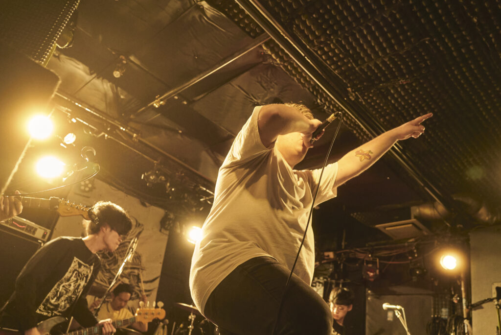 ライブの風景。ボーカルが指をさして歌っている。